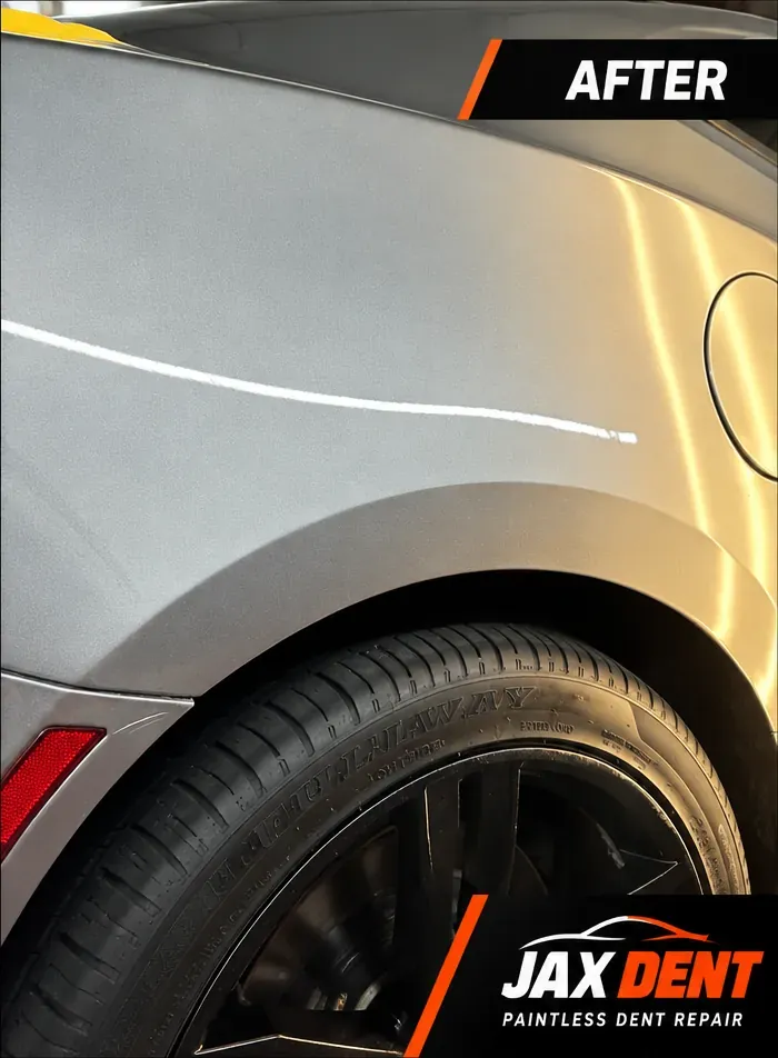 Rear quarter panel of the silver sedan after paintless dent repair with the wheel reinstalled