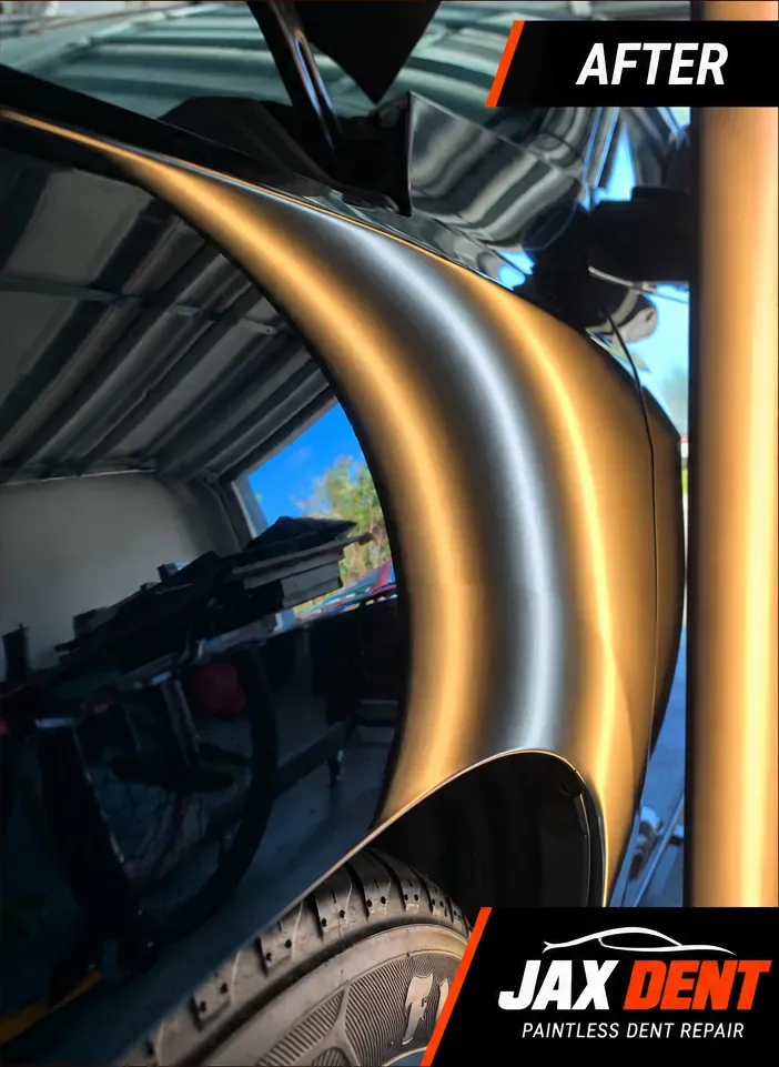 Rear quarter panel of the black vehicle after paintless dent repair, marked dents removed